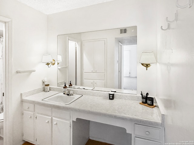 bathroom featuring visible vents, a textured ceiling, and vanity