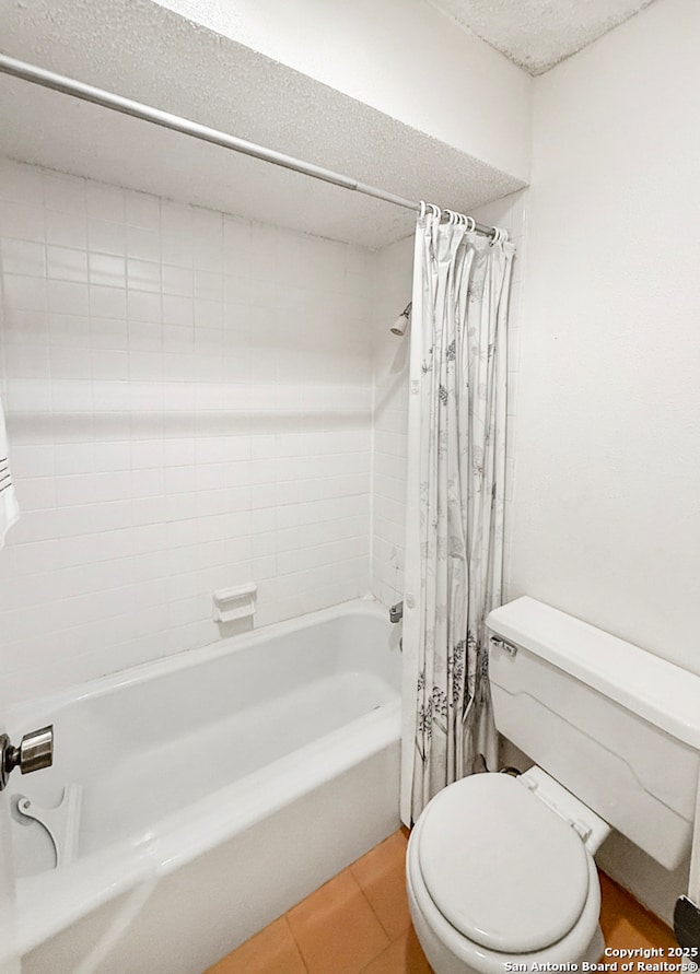 bathroom featuring tile patterned flooring, shower / tub combo, toilet, and a textured ceiling