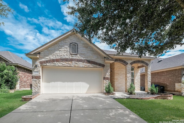 12535 Quarter J, San Antonio, TX 78254 - view of front of house with concrete driveway, an attached garage, stone siding, and a front yard