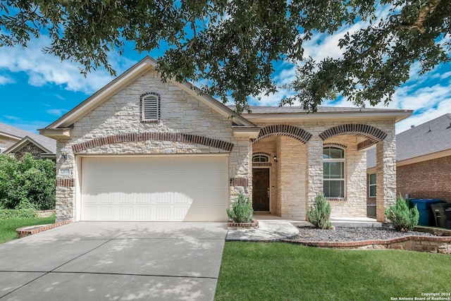 french country style house with a garage, stone siding, concrete driveway, and a front lawn