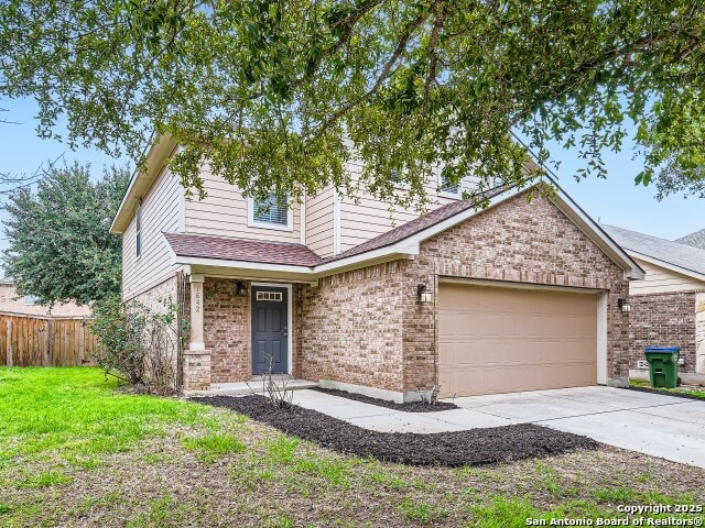 view of front of house featuring a front lawn, fence, concrete driveway, a garage, and brick siding