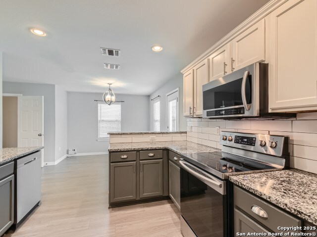 kitchen with a peninsula, tasteful backsplash, visible vents, and appliances with stainless steel finishes