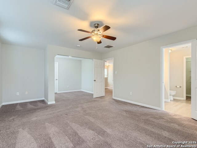 unfurnished bedroom featuring carpet flooring, baseboards, visible vents, and ensuite bathroom