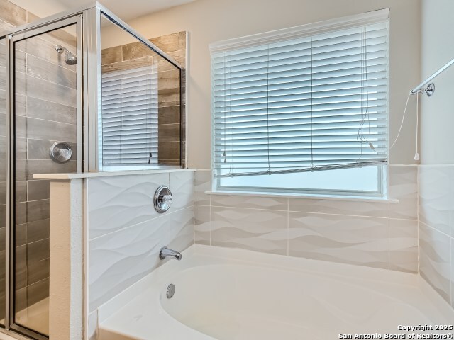 full bath with a garden tub and a stall shower