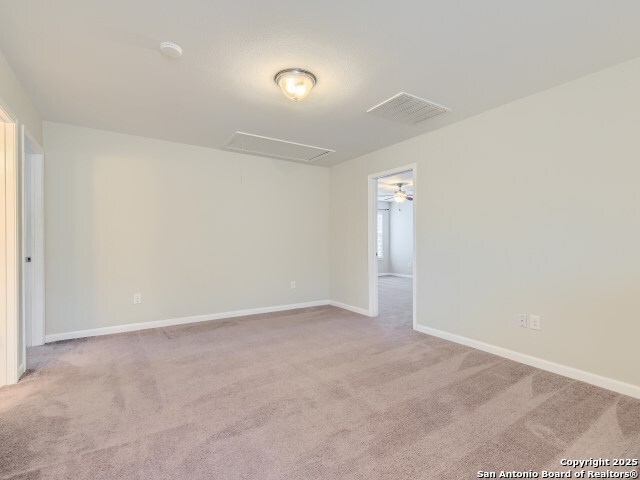 spare room featuring visible vents, baseboards, attic access, and carpet flooring