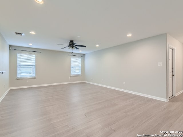 unfurnished room featuring visible vents, baseboards, light wood-style floors, and ceiling fan