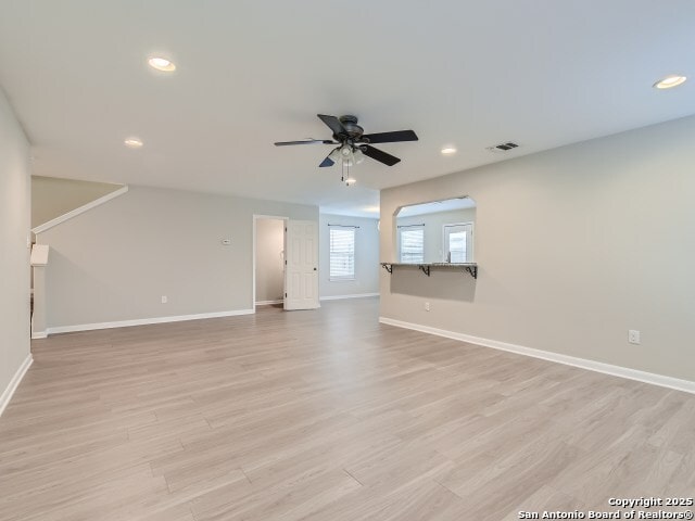 unfurnished living room featuring light wood-type flooring, visible vents, a ceiling fan, recessed lighting, and baseboards