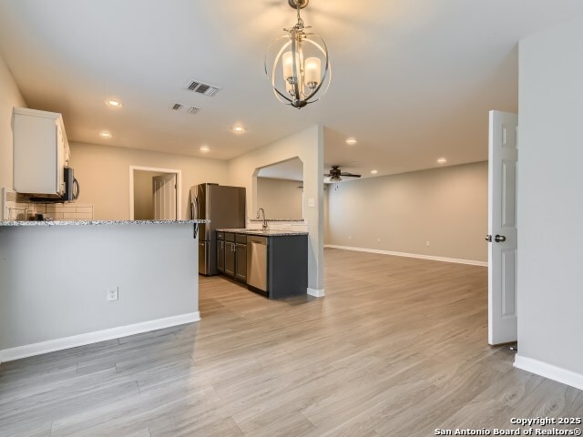 kitchen with light wood-style flooring, light stone countertops, visible vents, and appliances with stainless steel finishes