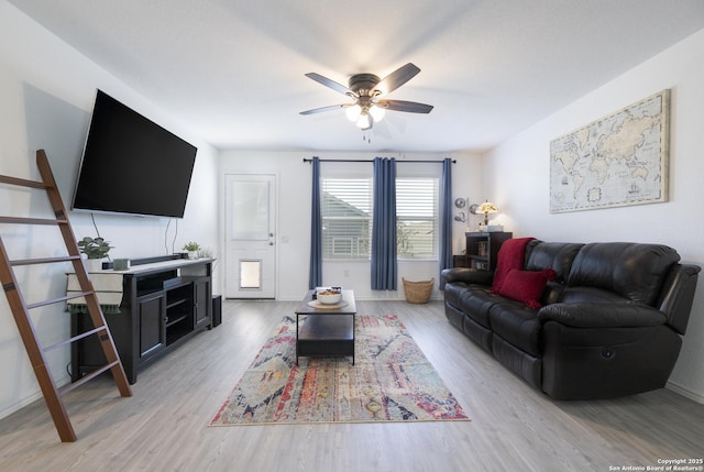 living room featuring light wood-style flooring, baseboards, and ceiling fan