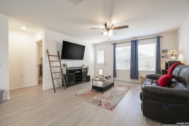 living room featuring visible vents, baseboards, light wood-type flooring, and a ceiling fan