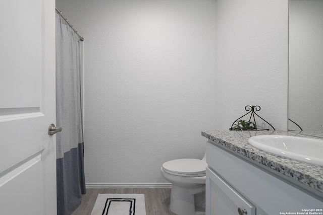 full bathroom with baseboards, toilet, a shower with curtain, wood finished floors, and vanity