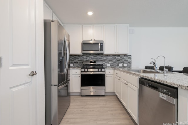 kitchen with white cabinetry, backsplash, appliances with stainless steel finishes, and a sink