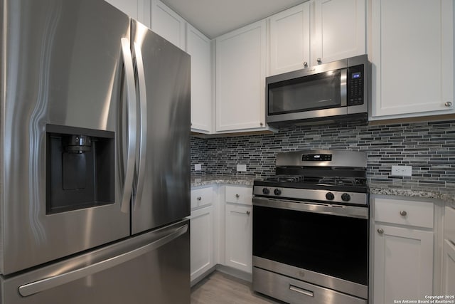 kitchen with decorative backsplash, white cabinets, and appliances with stainless steel finishes