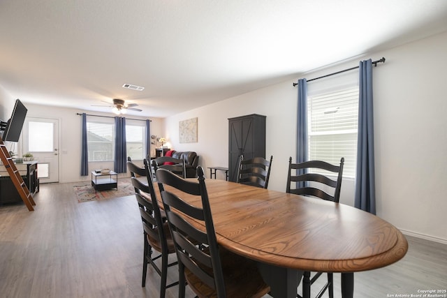 dining area featuring visible vents, baseboards, a ceiling fan, and wood finished floors