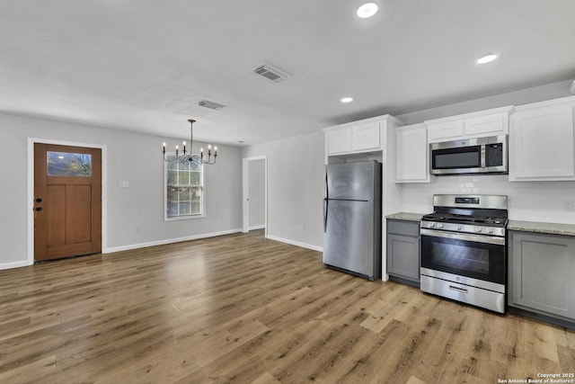 kitchen featuring visible vents, gray cabinetry, light wood-style floors, an inviting chandelier, and stainless steel appliances