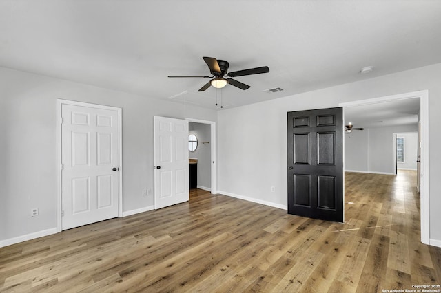 unfurnished bedroom featuring visible vents, baseboards, attic access, and hardwood / wood-style flooring