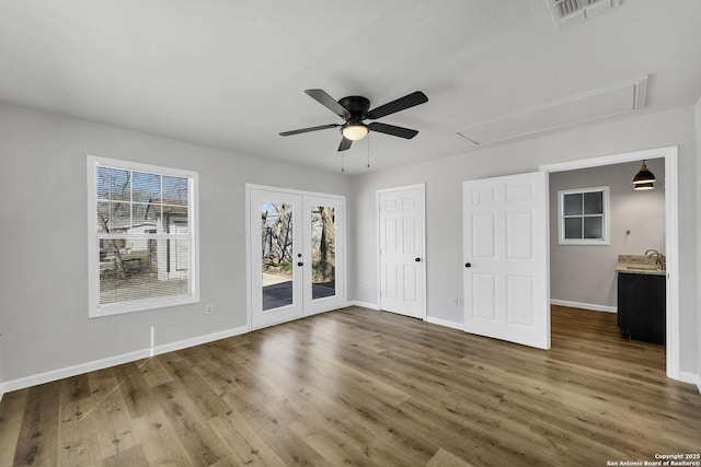 unfurnished bedroom with visible vents, access to outside, wood finished floors, french doors, and attic access