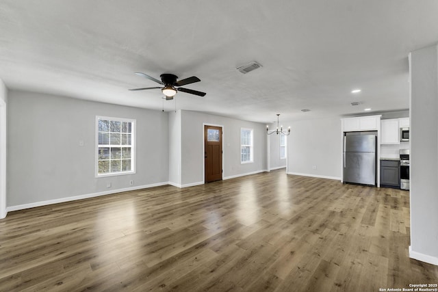 unfurnished living room featuring a wealth of natural light, visible vents, and wood finished floors