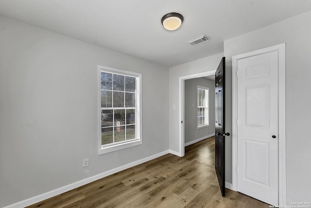 spare room featuring visible vents, baseboards, and wood finished floors