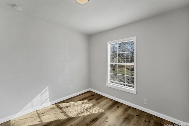 spare room featuring wood finished floors and baseboards