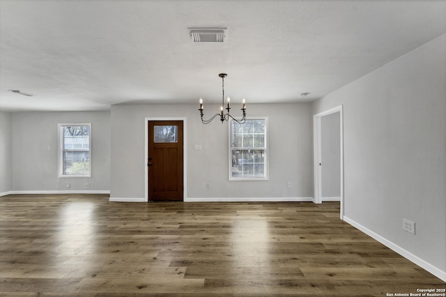 interior space with a wealth of natural light, visible vents, dark wood-type flooring, and an inviting chandelier