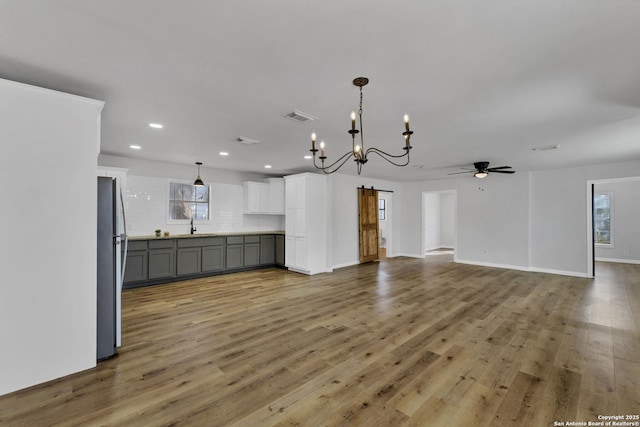 interior space featuring recessed lighting, visible vents, light wood-style flooring, and ceiling fan with notable chandelier