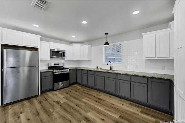 kitchen with gray cabinets, a sink, wood finished floors, white cabinetry, and stainless steel appliances