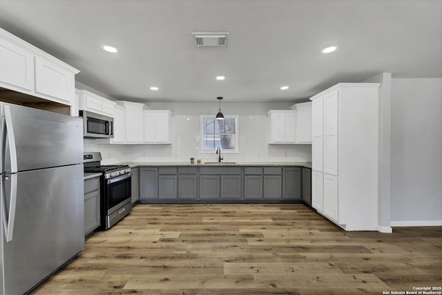 kitchen with light wood finished floors, visible vents, appliances with stainless steel finishes, and gray cabinetry