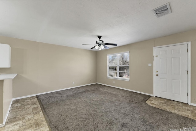 unfurnished living room featuring visible vents, baseboards, carpet flooring, a textured ceiling, and a ceiling fan