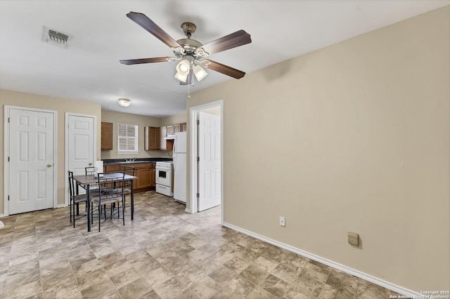 kitchen featuring dark countertops, visible vents, baseboards, white appliances, and a ceiling fan