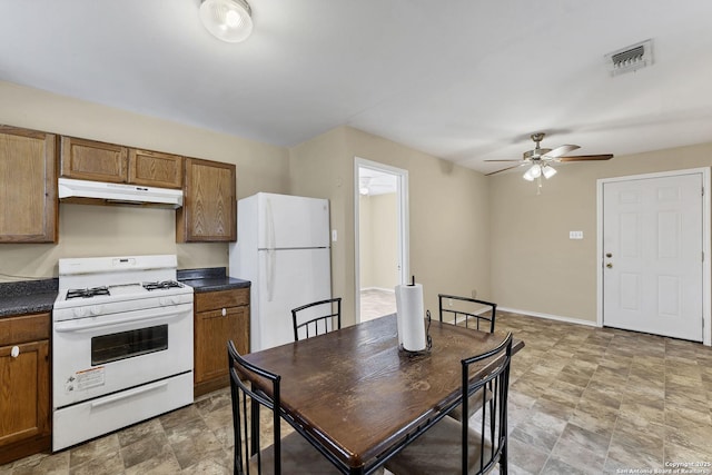 kitchen featuring visible vents, under cabinet range hood, dark countertops, white appliances, and ceiling fan