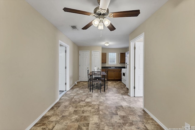 kitchen featuring visible vents, stone finish flooring, baseboards, gas range gas stove, and a ceiling fan