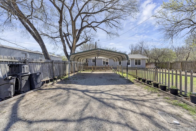 exterior space featuring a detached carport, aphalt driveway, and fence private yard