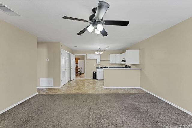 unfurnished living room with visible vents, light carpet, baseboards, and ceiling fan with notable chandelier