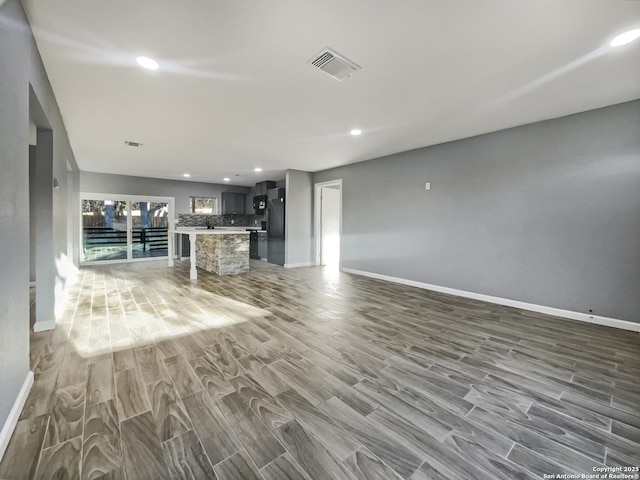 unfurnished living room featuring recessed lighting, visible vents, baseboards, and wood finished floors