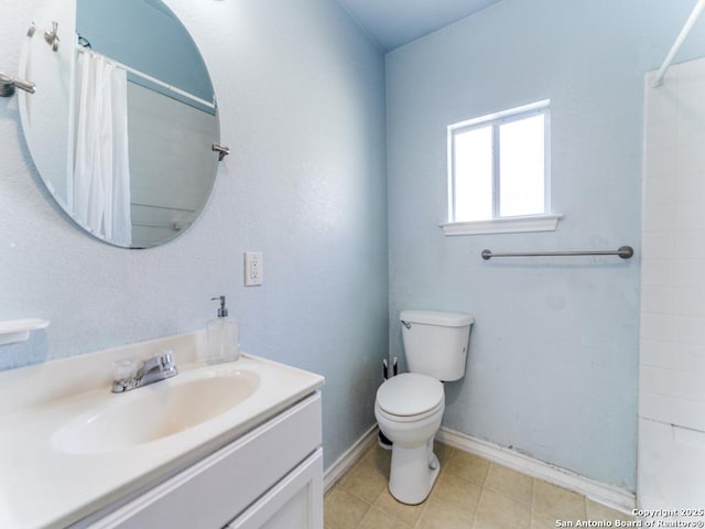 bathroom featuring vanity, toilet, baseboards, and tiled shower