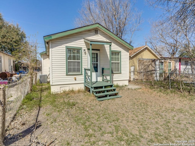 rear view of house featuring central AC unit and fence