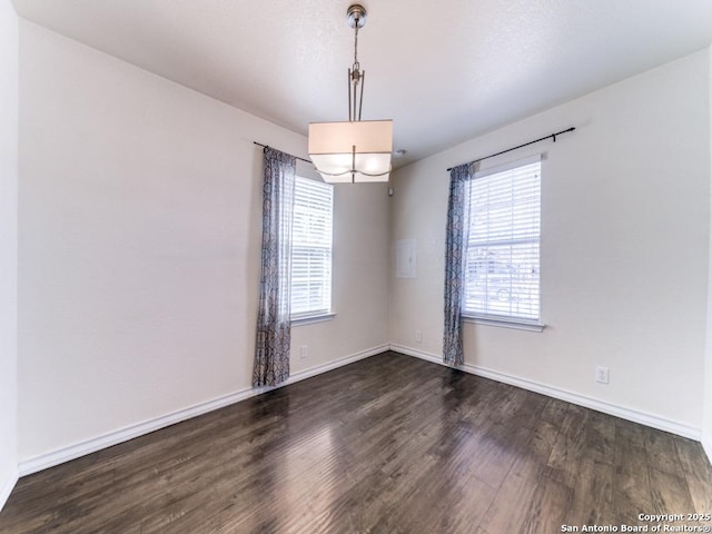 empty room with dark wood-style floors, baseboards, and a chandelier