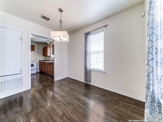 unfurnished dining area featuring a sink, visible vents, baseboards, and dark wood-style floors