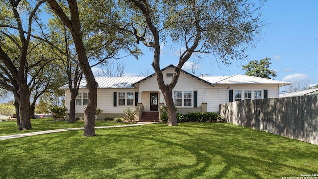 view of front of house featuring a standing seam roof, metal roof, a front yard, and fence