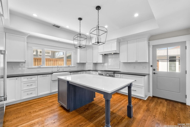 kitchen with visible vents, wood finished floors, a chandelier, and white cabinets