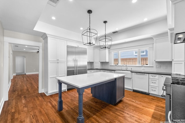 kitchen with a sink, built in fridge, an inviting chandelier, a breakfast bar area, and dishwasher