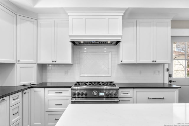 kitchen with tasteful backsplash, high end range, white cabinets, and dark stone countertops