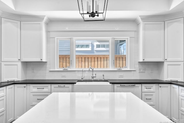 kitchen with white cabinetry, dark stone counters, tasteful backsplash, and a sink