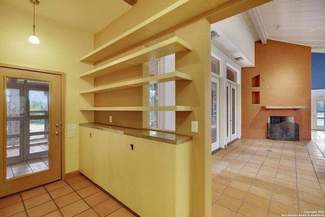 kitchen featuring hanging light fixtures, a fireplace, light tile patterned flooring, plenty of natural light, and open shelves