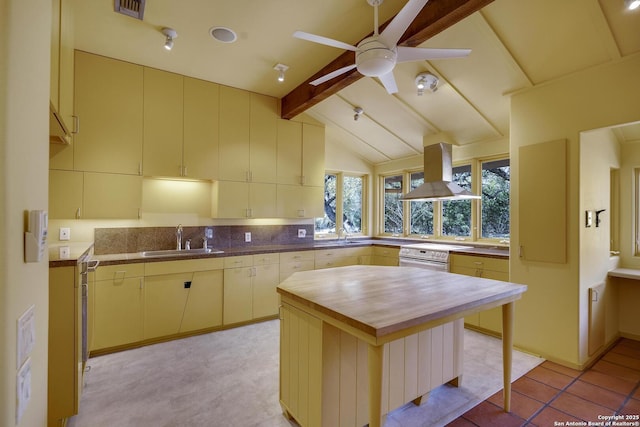 kitchen with a ceiling fan, vaulted ceiling with beams, a sink, wood counters, and island range hood