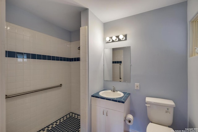 bathroom featuring tiled shower, toilet, and vanity