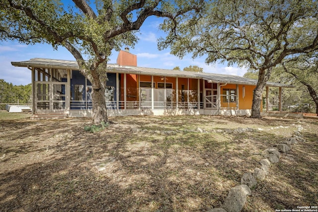 view of front of house with a sunroom and a chimney