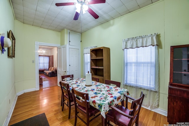 dining area featuring ceiling fan with notable chandelier, wood finished floors, and baseboards