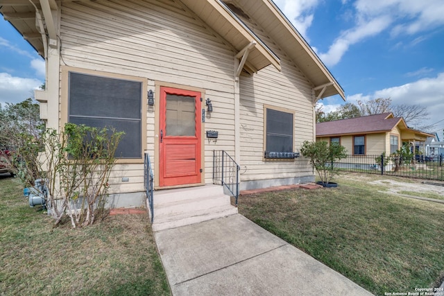 view of front of home featuring entry steps, a front lawn, and fence